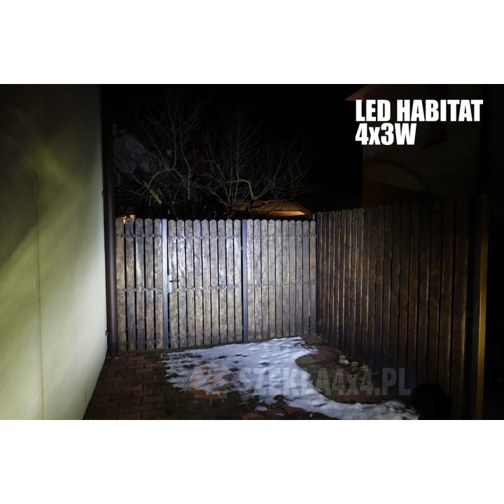 Sama lampa LED 4x3W Habitat – snop sięga górnej krawędzi płotu i gałęzi