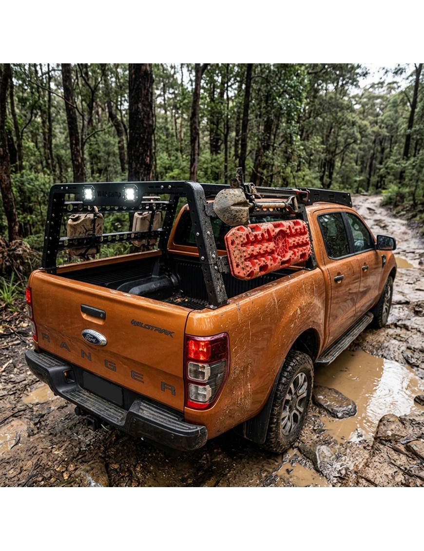 Pickup z bed rackiem Wild Camp z lampami LED i czerwonymi trapami na błotnistej drodze w lesie